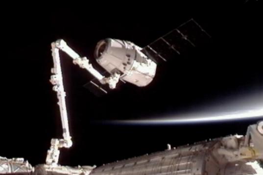 Esta imagen suministrada por NASA-TV muestra al vehículo comercial de carga Dragon de SpaceX, arriba, luego de ser asido por un brazo automático para conectarlo a la Estación Espacial Internacional el viernes 25 de mayo de 2012. SpaceX anunci...