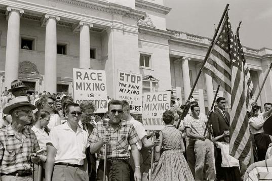 Un grupo de racistas porta banderas y carteles en contra de la mezcla racial en 1959, bajo lemas como "la mezcla racial es comunismo".
