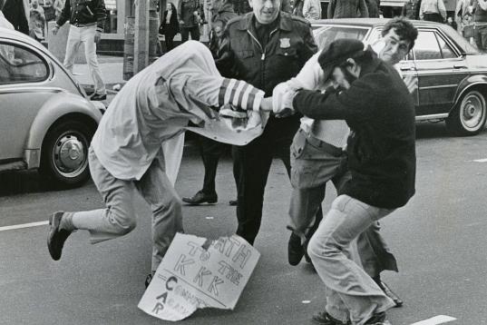 Un miembro del Ku Klux Klan y un manifestante por la igualdad pelean durante una marcha en Boston en 1978, frente a un policía que no hace nada.

