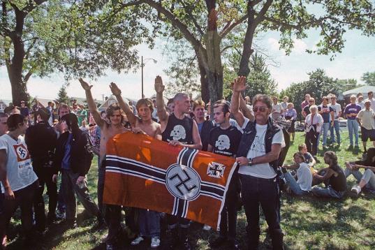 Un grupo de neonazis hacen el saludo de su grupo enarbolando una bandera nazi en Chicago en 1988.
