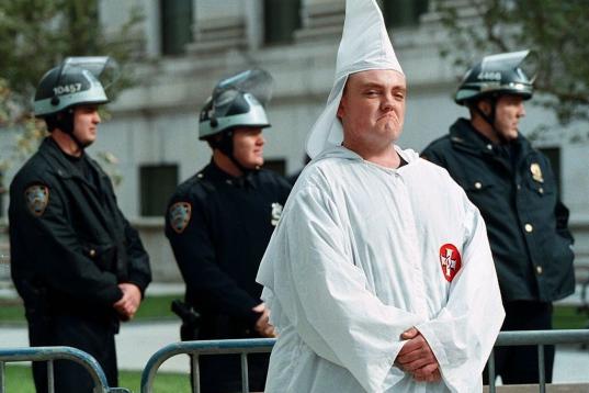 Un miembro del Ku Klux Klan posa arrogante tras una barrera policial para su protección durante una marcha en Nueva York en 1999.
