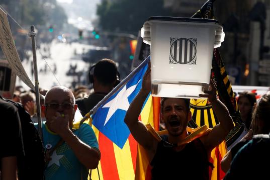 Un hombre porta una urna junto a otro con una bandera independentista catalana