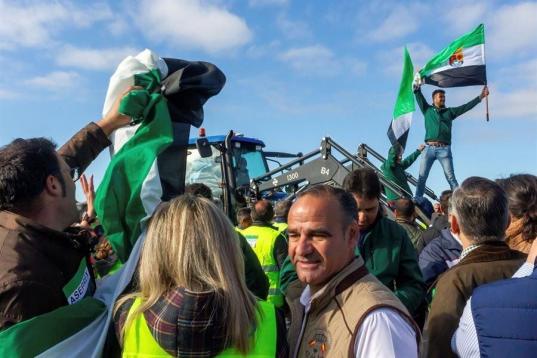 Muchos de los manifestantes han llegado en tractores que han dejado aparcados en las inmediaciones, ya que no tenían permiso para acceder con ellos a la vía, y algunos portan banderines de las organizaciones APAG Extremadura Asaja, UPA-UCE y COAG.