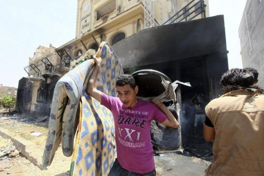Un opositor saca diversos objetos de la sede quemada de los Hermanos Musulmanes en El Cairo.