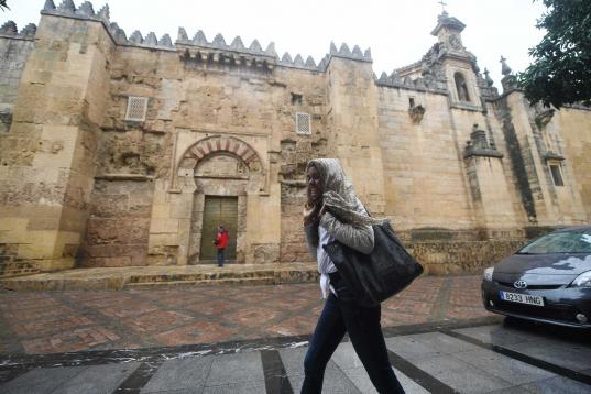 Una mujer se cubre la cabeza con un pañuelo para resguardarse de la intensa lluvia caía en Córdoba