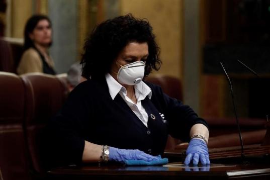 Una señora de la limpieza desinfecta el atril, este miércoles en el Congreso, tras la intervención del presidente del Gobierno, Pedro Sánchez.