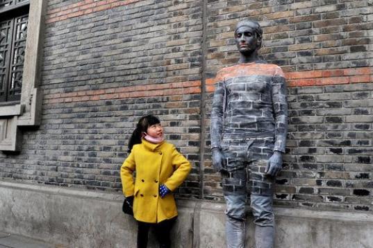 Una niña posa junto a un hombre camuflado en una parede en Shanghái, China.