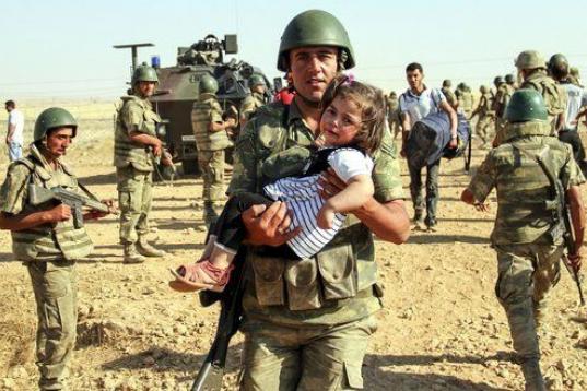 Un soldado turco lleva en brazos a una niña siria en la frontera de Akcakale.