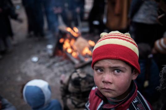Un niño trata de calentarse junto a un fuego en el patio de una casa, después de huir de los combates entre el ISIS y las fuerzas de seguridad iraquíes en Tall Kaysumah, al oeste de Mosul, Irak, el 4 de marzo de 2017. Luego,...