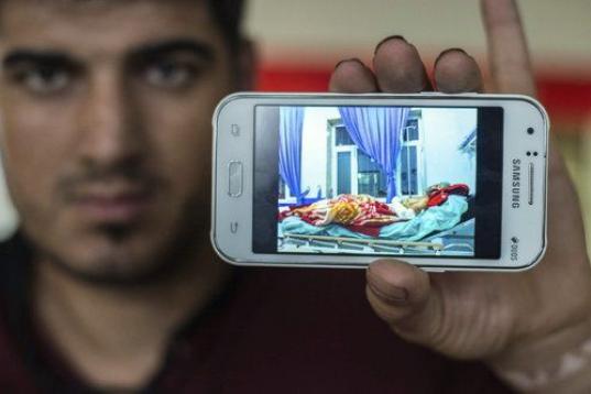 Un inmigrante iraquí muestra una fotografía en su teléfono móvil en la que, según dice, aparece él en la cama de un hospital tras un bombardeo, en la estación central de Stuttgart (Alemania).