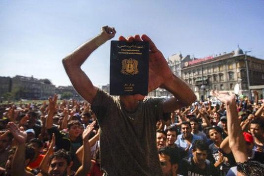 Un inmigrante muestra su pasaporte durante una manifestación, al no dejarlos subirse a los trenes, cerca a la Estación de Trenes Oriental en Budapest (Hungría). Una afluencia de inmigrantes a la Unión Europea presenta desafíos profundos, en...