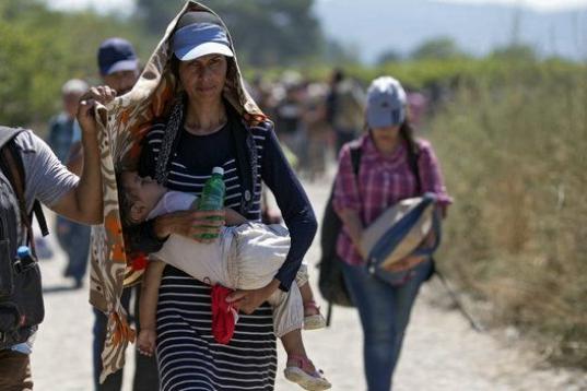 Varios refugiados cruzan la frontera entre Macedonia y Grecia, cerca del pueblo de Gevgelija, Macedonia. Las organizaciones que prestan ayuda a inmigrantes y refugiados señalan que unas 30.000 personas atraviesan la frontera a diario y que una ...