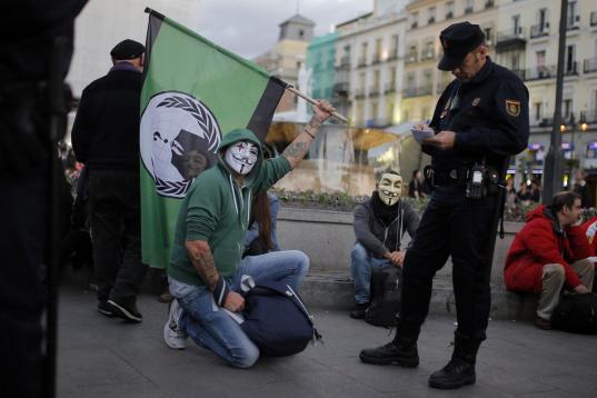Alterar el orden público encapuchado o con cualquier elemento que dificulte la identificación. En la imagen, un manifestante encapuchado y con máscara de Anonymous es identificado por la Policía en noviembre de 2013 en Madrid. 