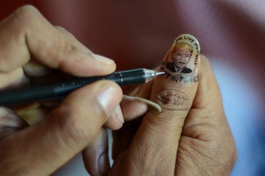 Una artista india pinta una miniatura de Mandela en una de sus uñas