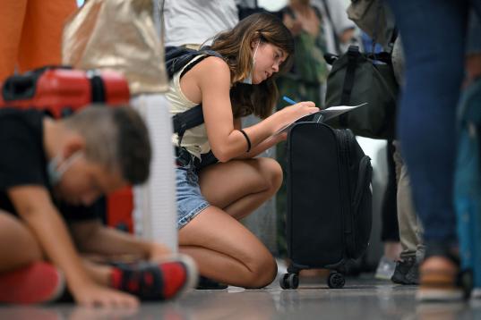 A passenger affected by the Ryanair strike fills out a claim form at the Terminal 2 of El Prat airport in Barcelona on June 30, 2022. - Around thirty Ryanair flights departing from and arriving in Spain were canceled, and 124 others were delayed...
