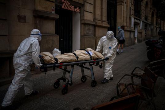 Empleados de una funeraria trasladan el cuerpo de un anciano fallecido por coronavirus en una camilla tras retirarlo de una residencia de mayores, en Barcelona, el 13 de noviembre de 2020. 