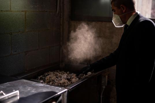 Un empleado del crematorio recoge las cenizas de un fallecido por covid en el tatatorio de Mémora, Girona. 