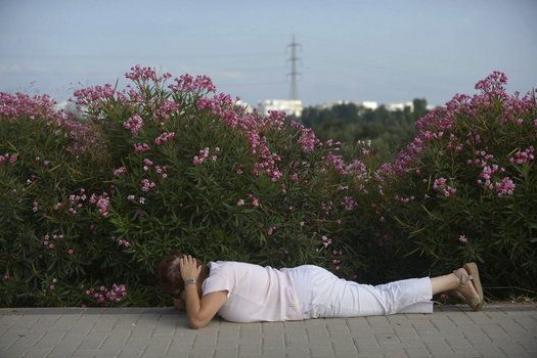 Una mujer israelí se cubre la cabeza y se tumba en el suelo mientras suenan las sirenas en la ciudad meridional de Ashdod (Israel). 
