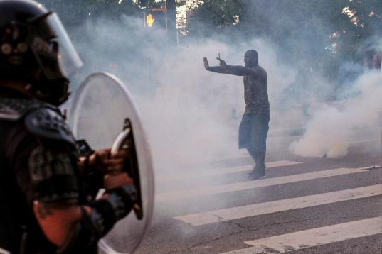 A protester tries to talk the police back amid tear gas in downtown Atlanta, Sunday, May 31, 2020. Protests continue across the country over the death of George Floyd, a black man who died after being restrained by Minneapolis police officers on...