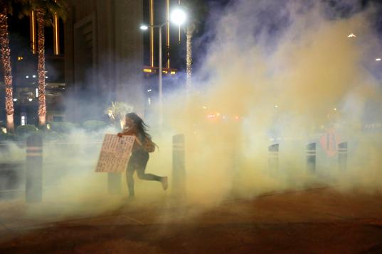A protester runs through tear gas on the Las Vegas Strip on Sunday, May 31, 2020, in Las Vegas, during demonstrations over the death of George Floyd, who died May 25 after he was pinned at the neck by a Minneapolis police officer. (AP Photo/Stev...