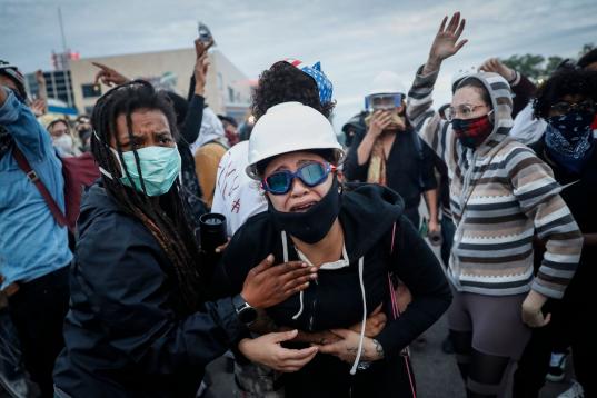 A protester reacts after being hit by crowd dispersal rounds as a group of demonstrators are detained prior to arrest at a gas station on South Washington Street, Sunday, May 31, 2020, in Minneapolis. Protests continued sparked by the death of G...