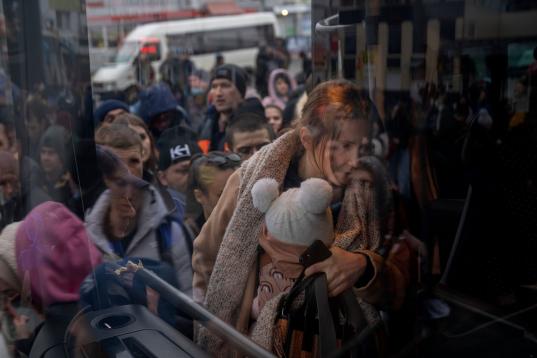 Una mujer sujeta su bebé mientras sube a un autobús para marcharse de Kiev. (AP Photo/Emilio Morenatti)