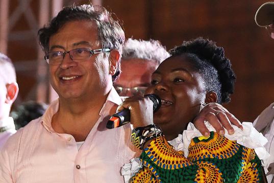 Colombian presidential candidate left-wing Gustavo Petro, listens to his Vice presidential formula Francia Marquez as she delivers a speech during a campaign rally in Cali, Colombia, May 19, 2022. - Petro is leading the polls for the upcoming pr...