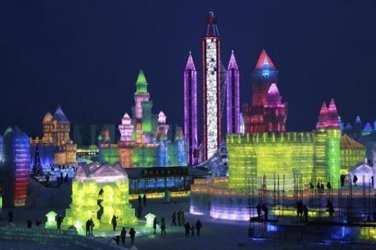 Los visitantes se acercan a las esculturas de hielo iluminadas para el festival internacional de figuras de nieve y hielo de Harbin (China).