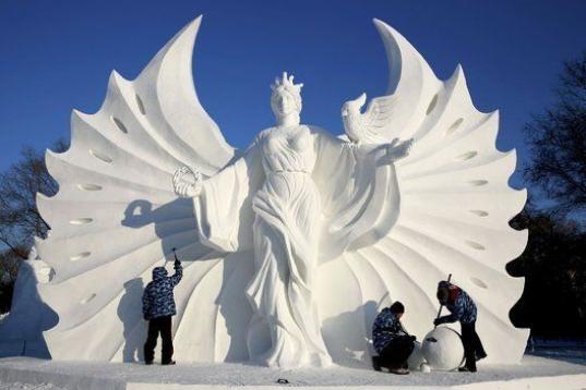 Varios trabajadores pulen una escultura de nieve de cara a la 16ª edición del festival internacional de figuras de nieve y hielo de Harbin (China).