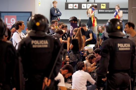 Agentes de los Mossos d' Esqueadra vigilan en El Prat a los manifestantes que han ocupado la terminal 1 del aeropuerto