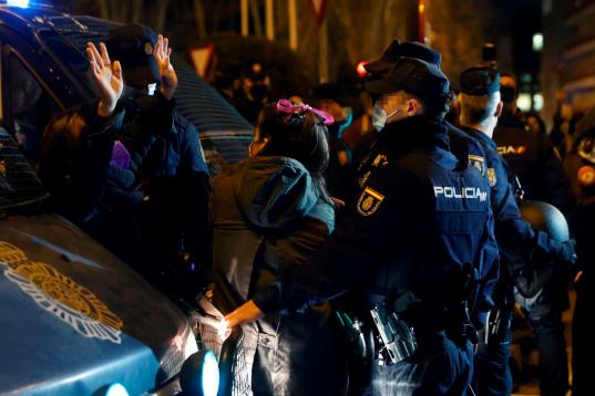 Efectivos policiales vigilan a asistentes a una sentada improvisada en la plaza de Neptuno de Madrid con motivo de la celebración del Día Internacional de la Mujer.
