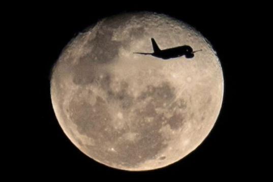 Un avión que despega desde Rio de Janeiro, Brasil, vuela frente a la luna. 