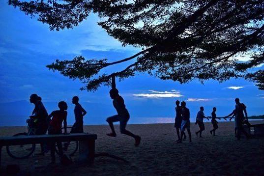 Un chico se balancea de una rama de un árbol en una playa de Bujumbura. 