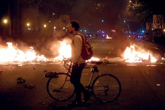 Un ciudadano, con su bicicleta, pasa por una barrera de fuego