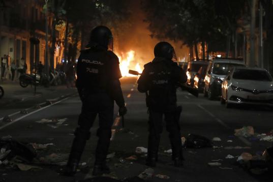 Dos agentes avanzan entre los destrozos en una calle de Barcelona