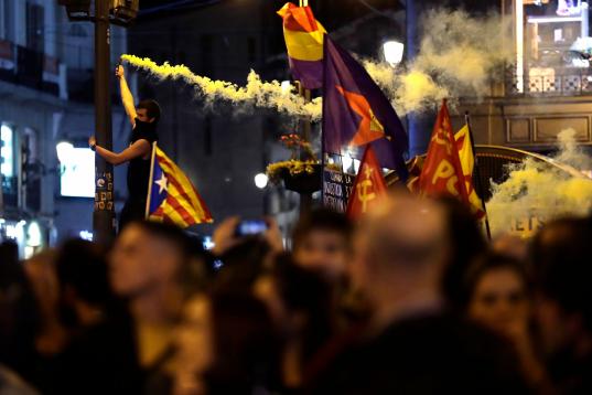 A protestor burns a flare as a pro-independence Estelada flag is waved in Puerta del Sol square in Madrid, Spain, Wednesday, Oct. 16, 2019. Spain's government said Wednesday it would do whatever it takes to stamp out violence in Catalonia, where...