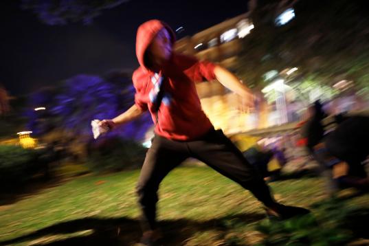 A protestor hurls a rock at police during clashes in Barcelona, Spain, Wednesday, Oct. 16, 2019. Spain's government said Wednesday it would do whatever it takes to stamp out violence in Catalonia, where clashes between regional independence supp...