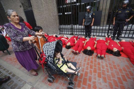 Activistas vestidas de rojo protestan delante del Ministerio de la Mujer de Lima en lo que representa una "alfombra roja" humana como símbolo de que los derechos de las mujeres están siendo pisoteados por el Gobierno.