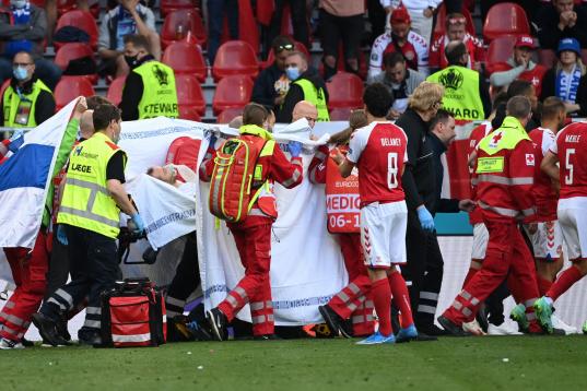 Medics stretcher Denmark's midfielder Christian Eriksen off the pitch after he collapsed during the UEFA EURO 2020 Group B football match between Denmark and Finland at the Parken Stadium in Copenhagen on June 12, 2021. (Photo by Jonathan NACKST...