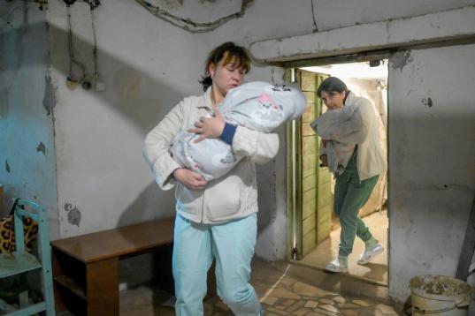 Unas enfermeras llevan a los bebés al refugio de la clínica de Mykolaiv.