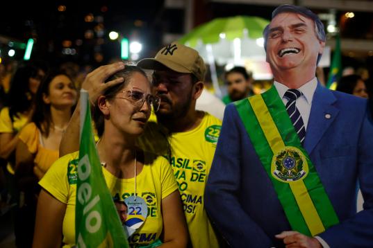 Una mujer simpatizante de Bolsonaro lamenta los resultados electorales al lado de un cartel a tamaño real del mandatario.