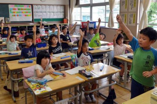 El alumno de la escuela de primaria Seishi Nishida levanta la mano junto a sus compañeros de clase en Tokio, el 11 de junio de 2013.