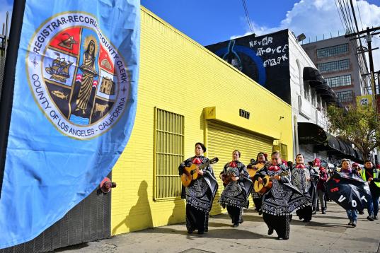 Un grupo de mariachis lidera a un grupo de latinos hacia el centro de votación en Los Angeles, California. 