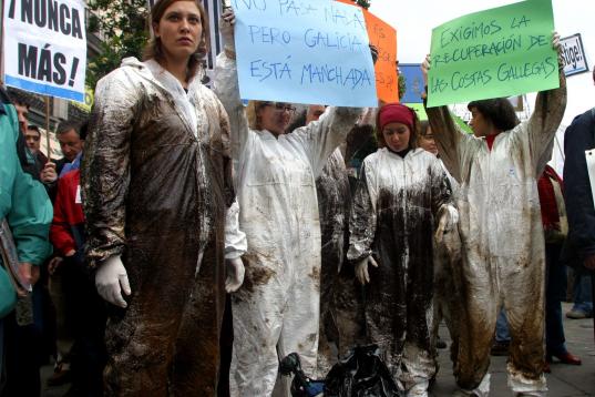 Voluntarios manifestándose en la Puerta de Sol en Madrid, con los trajes manchados de crudo.