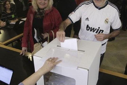 Un ciudadano, vestido con la camiseta del Real Madrid, deposita su papeleta, en el Institut Montserrat de Barcelona.