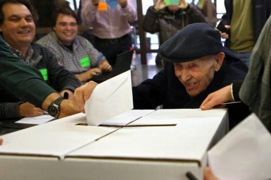 Un anciano de 93 deposita su papeleta en un local de la Vía Augusta de Barcelona, durante la jornada participativa.