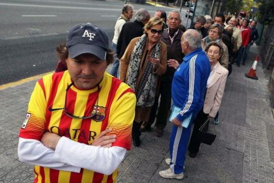 Colas de ciudadanos esperan en la Vía Augusta de Barcelona la apertura de uno de los centros de votación habilitados por el Govern