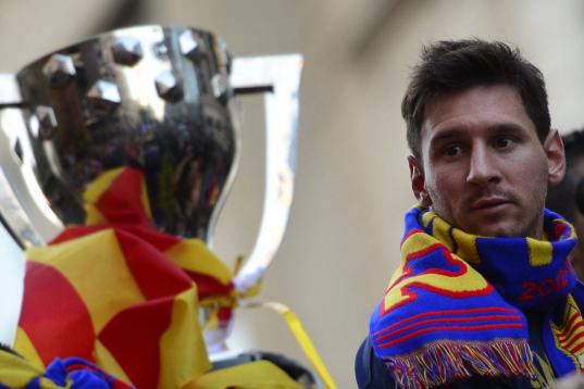 Barcelona's Argentinian forward Lionel Messi looks at the cup as he and his teammates parade on a bus through a crowd of supporters celebrating in the streets of Barcelona on May 13, 2013, two days after their team won the Spanish league. The Ca...