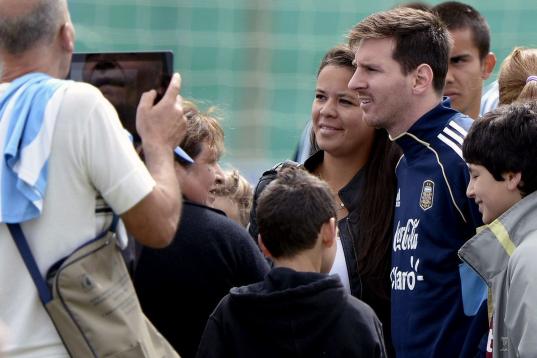 Argentina's forward Lionel Messi (C) poses for pictures with supporters during a training session in Ezeiza, Buenos Aires on March 19, 2013 ahead of the Brazil 2014 FIFA World Cup South American qualifier football match against Venezuela on Marc...