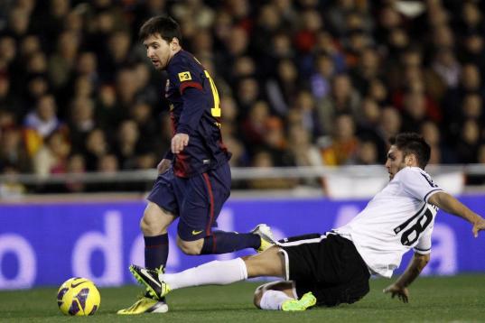 Barcelona's Lionel Messi from Argentina, left, duels for the ball with Valencia's Victor Ruiz, during their La Liga soccer match at the Mestalla stadium in Valencia, Spain, Sunday, Feb. 3, 2013. (AP Photo/Alberto Saiz)